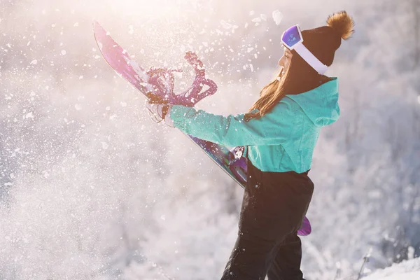 Отдых, спортивная концепция. Сноубордистка держит доску и искры снега . — стоковое фото