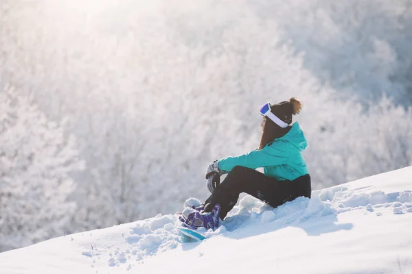 Nainen lumilautailija istuu korkealla kukkulalla ja levätä — kuvapankkivalokuva