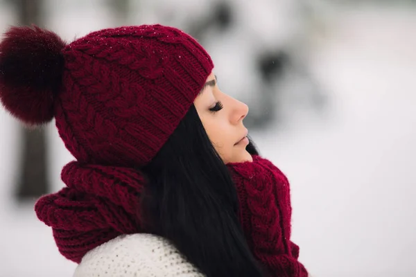 Cute woman profile in wool hat and mittens at frosty winter day