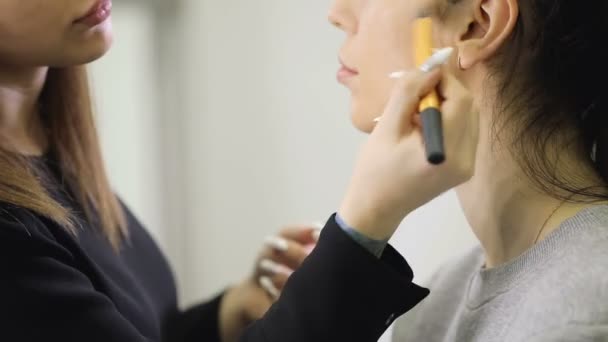 Визажист делает макияж для модели девушки в салоне — стоковое видео