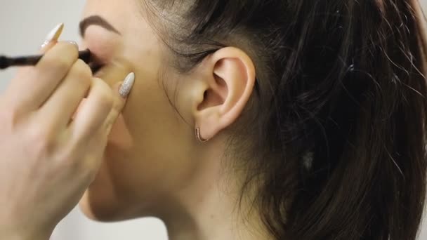 Крупным планом визажист делает макияж, добавляет тени на глаз с кистью — стоковое видео