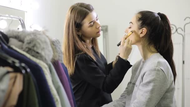 Visagista haciendo maquillaje usando cepillo para chica modelo en el salón — Vídeo de stock