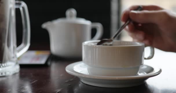 Persoon hand mengen van suiker in een kopje thee en het drinken van drank — Stockvideo