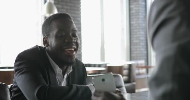 Afrikanska killkompisar pratar i café, visar foton på smart phone — Stockvideo