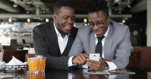 African man friends talking in cafe, looking photos together on smart phone — Stock Video