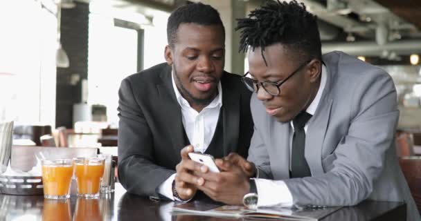 Afrikalı işadamları arkadaşlar komik fotoğraflar birlikte kafede akıllı telefon üzerinde tartışıyor. — Stok video