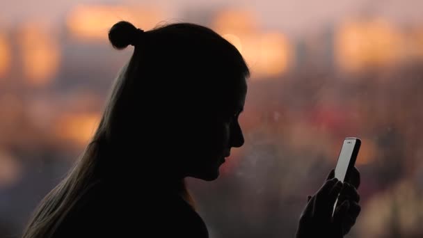 Sylwetka kobiety za pomocą inteligentnego telefonu w domu stojąc w pobliżu okna — Wideo stockowe