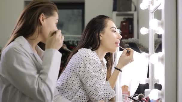 Mulheres bonitas amigas fazendo maquiagem em pé diante do espelho — Vídeo de Stock