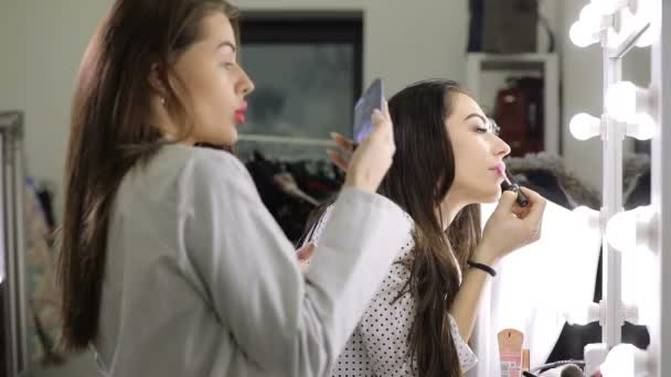 Смешные девушки собираются, они делают макияж стоя перед зеркалом — стоковое видео