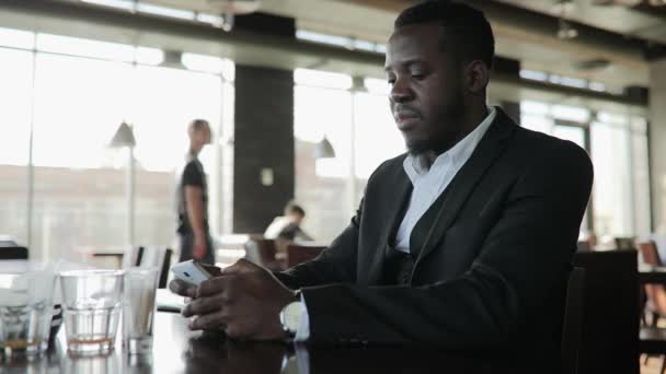 Afrikaanse zakenman praten door slimme telefoon in café — Stockvideo