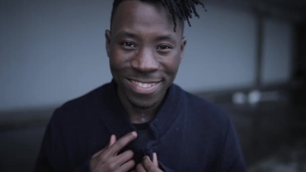 Черно-африканский портрет улыбающегося мужчины, смотрящего в камеру в городском месте — стоковое видео