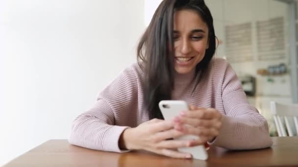Красивая раздраженная женщина с помощью приложения для смартфонов сидит в кафе — стоковое видео