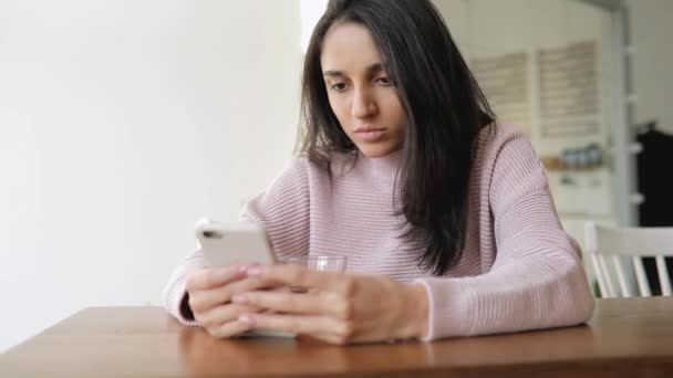 Mujer cansada usando aplicación para teléfonos inteligentes sentada en un café — Vídeo de stock