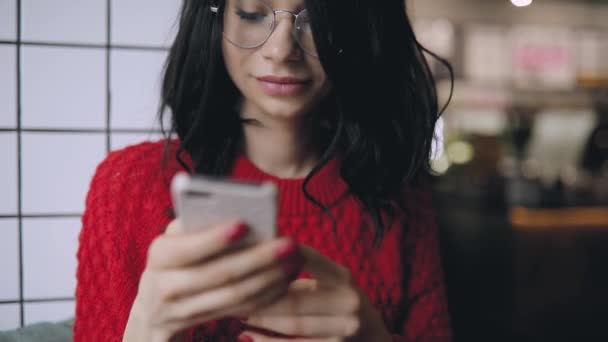Γυναίκα σε γυαλιά χρησιμοποιώντας κινητή συσκευή που κάθεται στο παράθυρο — Αρχείο Βίντεο