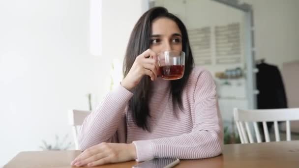 Gyönyörű nő teát iszik egy kávézóban. — Stock videók