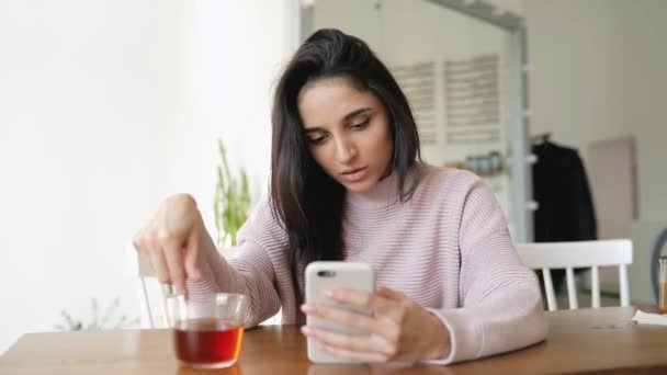 Hermosa mujer usando aplicación de teléfono inteligente sentado en una taza giratoria café — Vídeo de stock