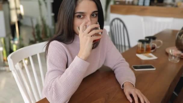 Schöne Frau trinkt Tee in einem Café — Stockvideo