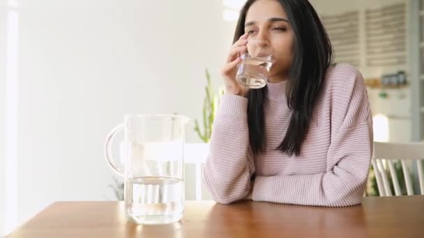 Красива жінка п'є воду, сидячи в кафе — стокове відео