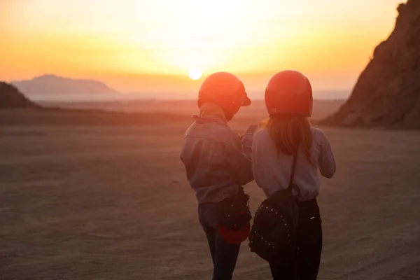 Las mujeres turistas con casco, amanecer por la mañana en el desierto, vista trasera, mirando smartphone —  Fotos de Stock