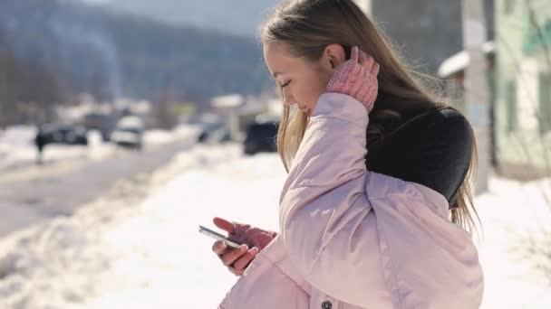 Vrouw met behulp van slimme telefoon in winter city straat in slow motion — Stockvideo