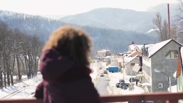 Krullend haar leuke vrouw op zoek naar winter mountain, zet gezicht en glimlach — Stockvideo