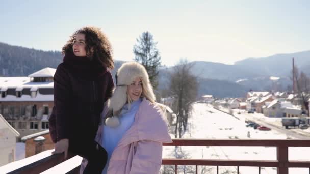 Счастливые женщины-друзья улыбаются в камеру, сидя на мосту — стоковое видео