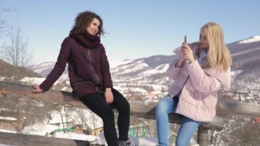 İki kız arkadaş birbirlerine karlı dağlar arka plan üzerinde fotoğraf çekimi