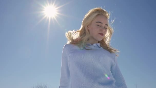 Jonge blonde vrouw poseren tegen zonnige hemelachtergrond — Stockvideo