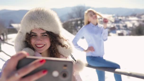 Chicas amigos haciendo foto móvil en el paisaje de montaña nevado — Vídeo de stock