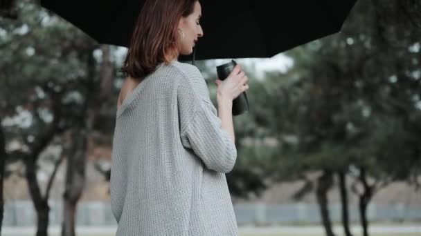 Femme sous parapluie buvant du café — Video