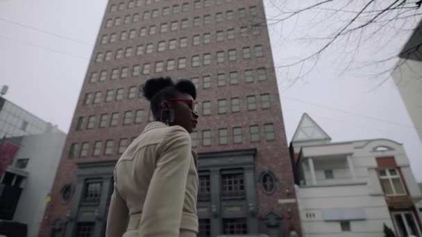 Femme à la mode regardant autour des bâtiments dans le centre-ville avec les mains levées — Video