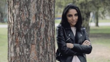 Çekici bir kadın ayakta yaslanmış ağaç üzerinde