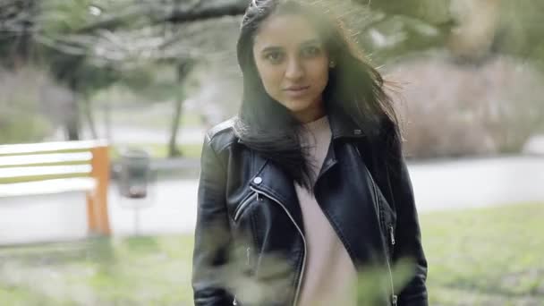 Jolie femme brune dans un parc marchant entre les branches d'arbres — Video