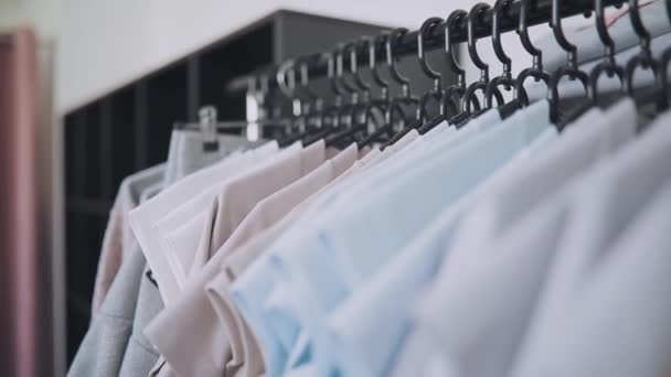 Fila de ropa en perchas en la tienda — Vídeos de Stock