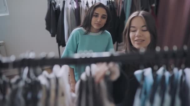 Mujer elegir ropa en la tienda, vendedor ayudarla — Vídeo de stock