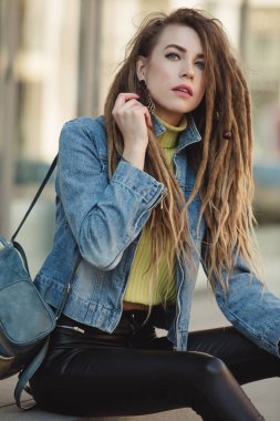 Denim ceket sokakta oturan dreadlocks ile şık kadın