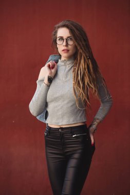 Kırmızı duvar arka planı poz dreadlocks ile şık kadın