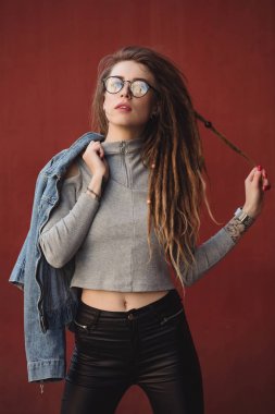 Kırmızı duvar arka planı poz dreadlocks ile şık kadın