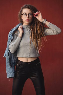 Kırmızı duvar arka planı poz dreadlocks ile şık kadın