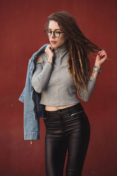 Femme élégante avec dreadlocks posant sur fond de mur rouge — Photo