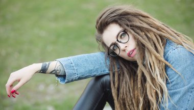 Şık kadınla çimenlerin üzerinde oturan dreadlocks saç modeli portresi