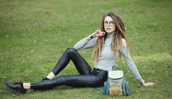 Stylische Frau mit Tasche auf Gras sitzend — Stockfoto