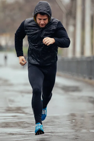 Sports man jogging on the bridge in rainy day