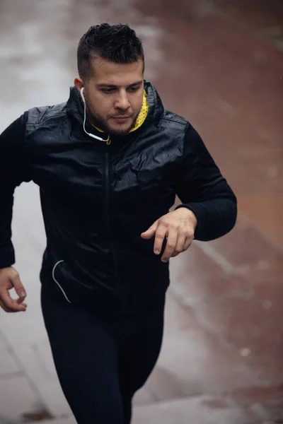 Sports man jogging outdoors in rainy day