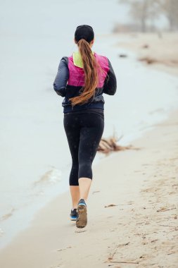 Yağmurlu günde, dikiz nehir sahilde koşu kadın