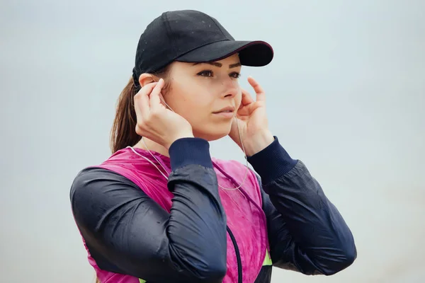 Retrato de mujer deportiva en gorra en el día lluvioso, ella usando auriculares — Foto de Stock