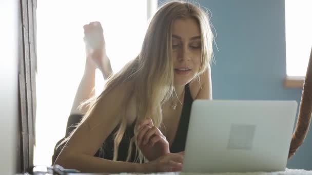 Mujer sexy freelancer trabajando por computadora portátil tumbado en un piso en casa — Vídeos de Stock