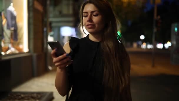 Mujer hablando por teléfono inteligente caminando por la calle de la noche — Vídeos de Stock