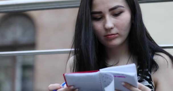 Дівчинка-підліток пише нотатки в книзі — стокове відео