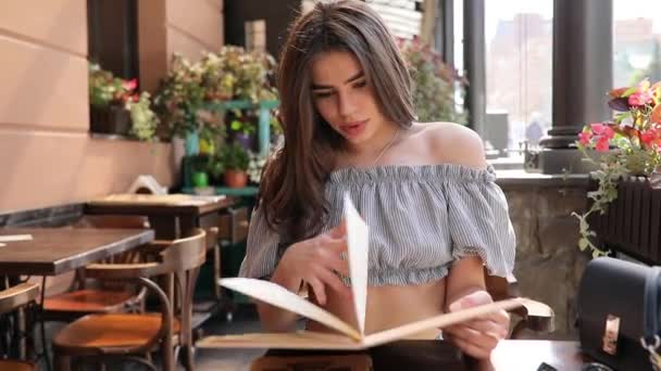 Mooie vrouw lezen van een menu in een restaurant — Stockvideo